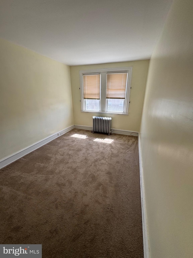 carpeted spare room with baseboards and radiator