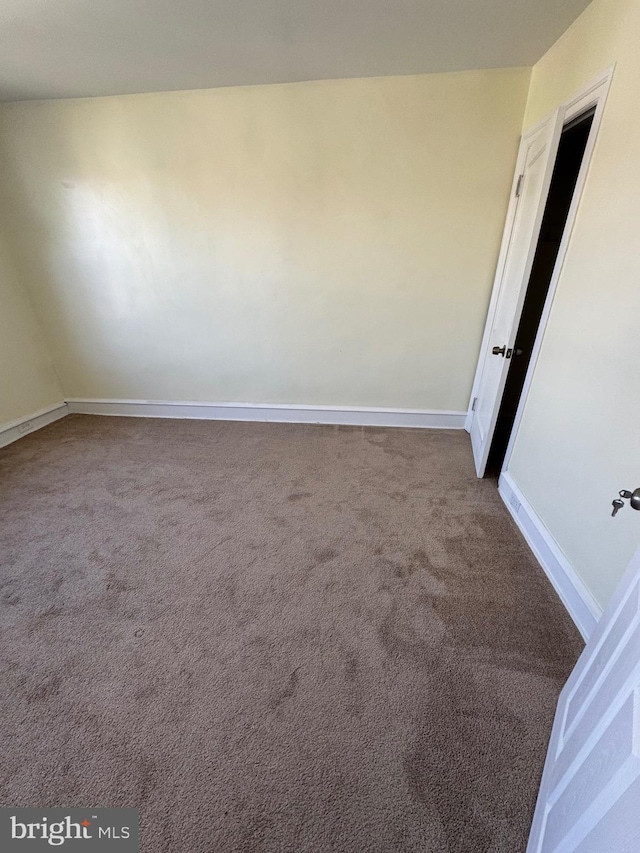 spare room with baseboards and carpet