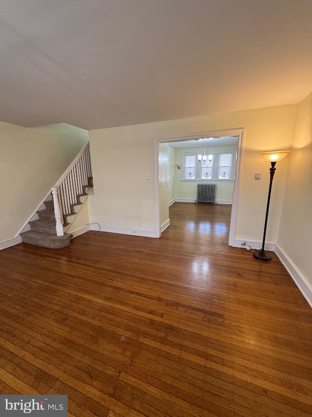 interior space with dark wood-style flooring, baseboards, a notable chandelier, and radiator