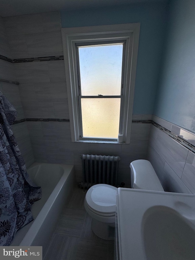 bathroom with toilet, tile walls, and radiator heating unit