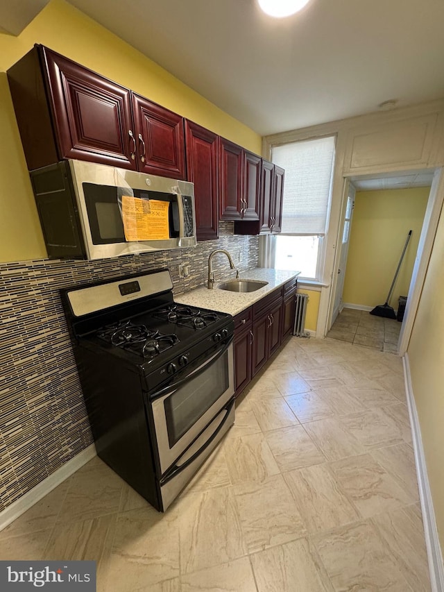 kitchen with backsplash, dark brown cabinets, a sink, baseboards, and stainless steel appliances