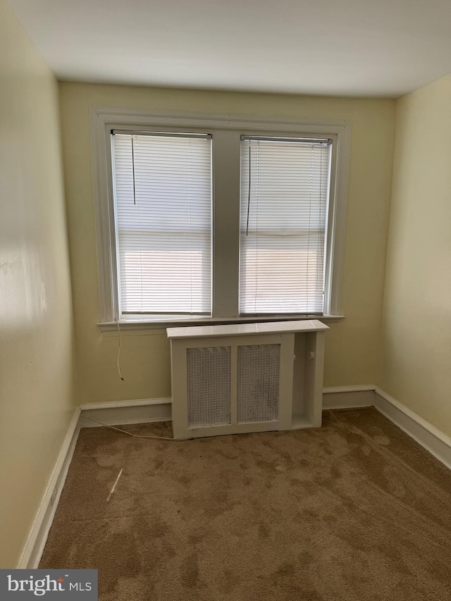 unfurnished room with radiator heating unit, baseboards, and carpet flooring