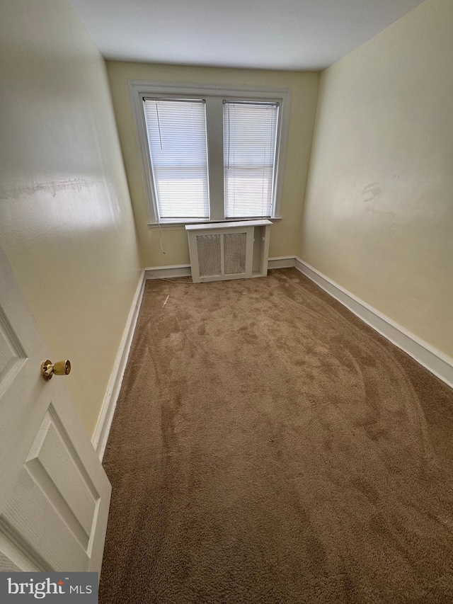 spare room with radiator heating unit, baseboards, and carpet