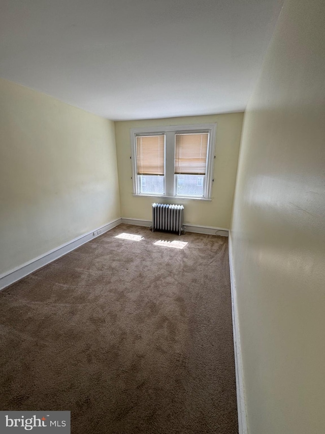 spare room featuring radiator, baseboards, and carpet flooring