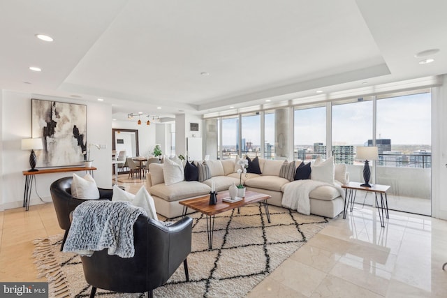 living room with a wall of windows, a tray ceiling, and recessed lighting