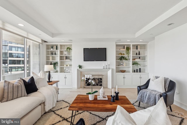 living area with a high end fireplace, a raised ceiling, and built in features