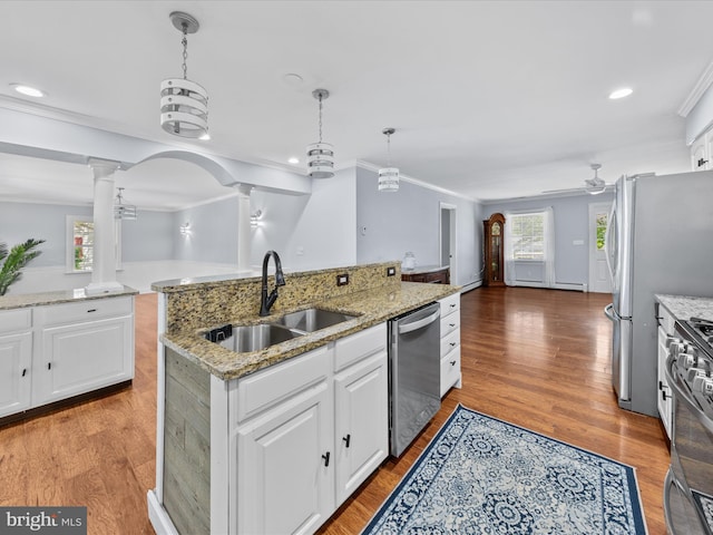 kitchen featuring white cabinetry, a sink, appliances with stainless steel finishes, ornamental molding, and decorative columns