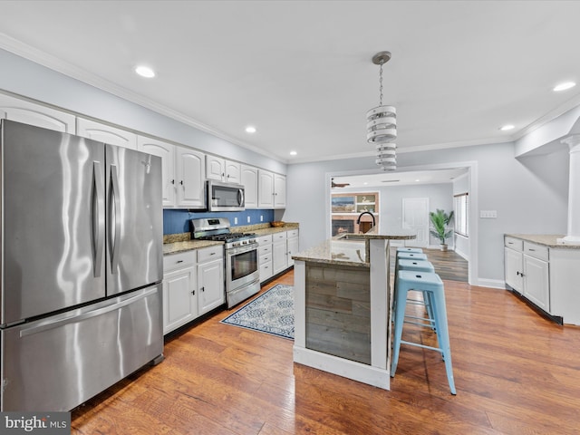 kitchen with crown molding, light stone countertops, white cabinets, and appliances with stainless steel finishes