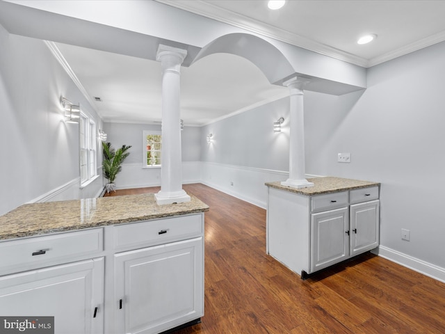 kitchen with light stone countertops, ornamental molding, dark wood-style floors, and decorative columns