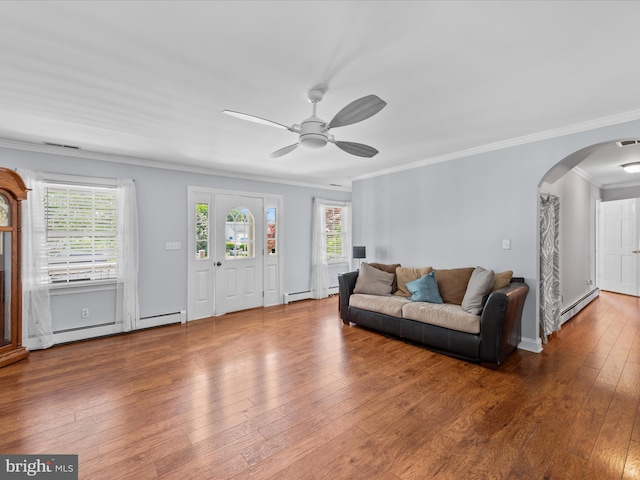 living room featuring a baseboard heating unit, a wealth of natural light, arched walkways, and crown molding