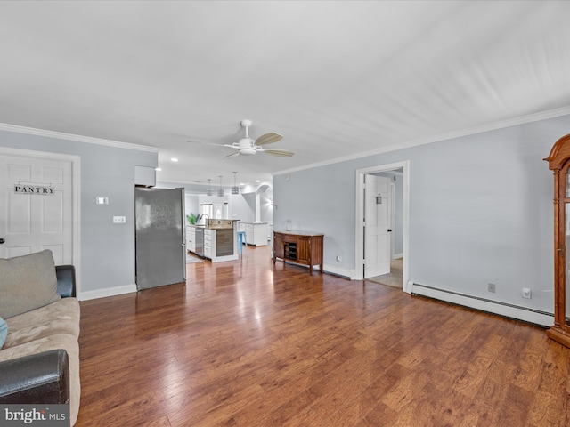 unfurnished living room with baseboard heating, ornamental molding, and a ceiling fan