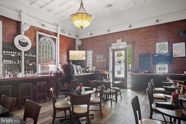 interior space with a dry bar, an ornate ceiling, wood finished floors, and brick wall