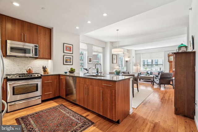 1425 Locust St Unit 10C, Philadelphia, PA 19102 - kitchen featuring stainless steel appliances, a peninsula, brown cabinets, a sink, and tasteful backsplash