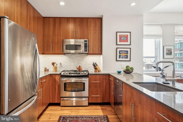 1425 Locust St Unit 10C, Philadelphia, PA 19102 - kitchen with appliances with stainless steel finishes, a sink, stone counters, brown cabinets, and light wood finished floors