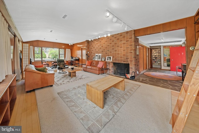 living room with a brick fireplace, hardwood / wood-style floors, and visible vents