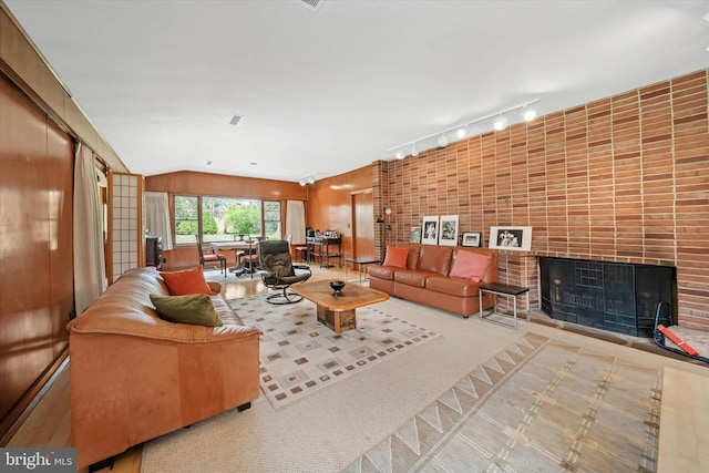 living room featuring rail lighting, a fireplace, and vaulted ceiling