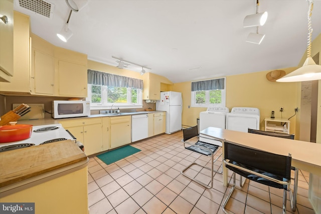 kitchen with a sink, white appliances, rail lighting, a wealth of natural light, and washing machine and dryer