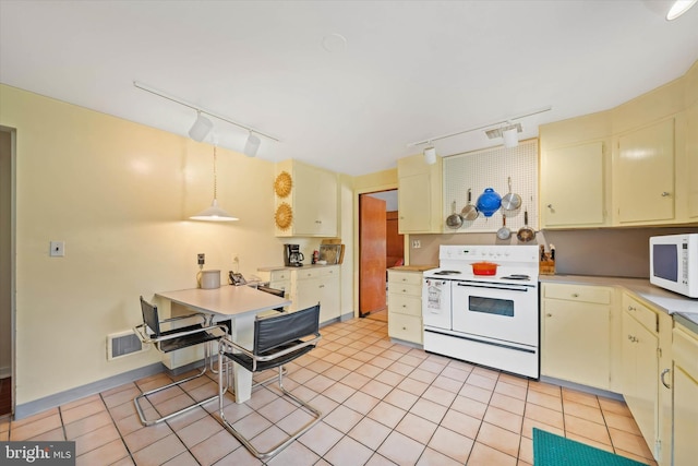 kitchen featuring rail lighting, light countertops, cream cabinets, and white appliances