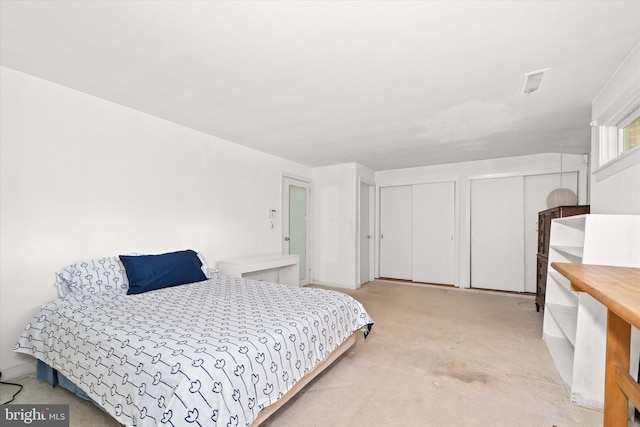 bedroom with carpet flooring, multiple closets, and visible vents