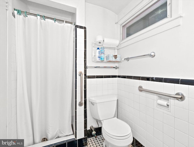 full bath featuring wainscoting, toilet, a shower with curtain, and tile walls