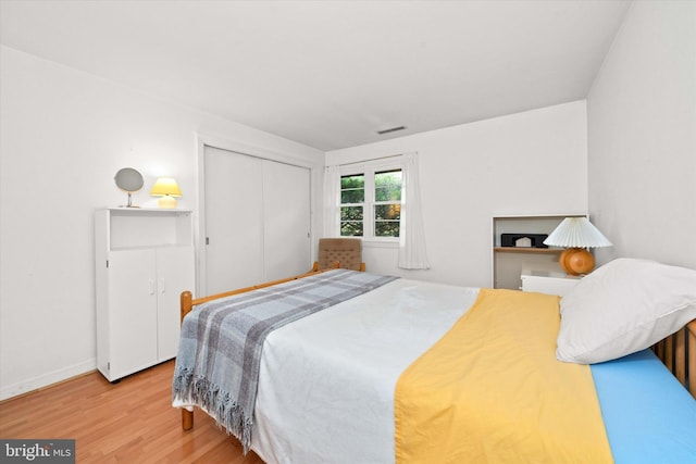 bedroom featuring a closet, visible vents, wood finished floors, and baseboards