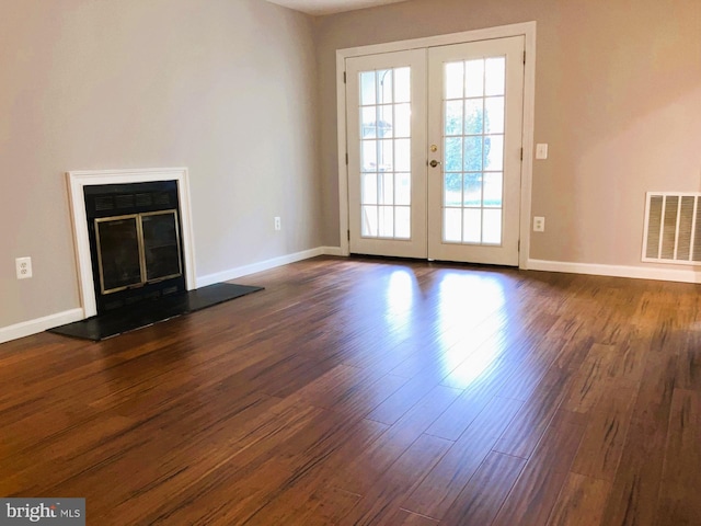 unfurnished living room featuring french doors, dark wood-style floors, baseboards, and a glass covered fireplace
