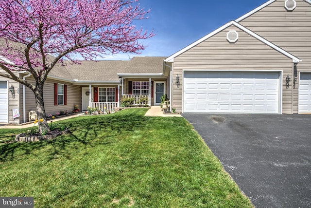view of front of house with an attached garage, driveway, a front lawn, and covered porch