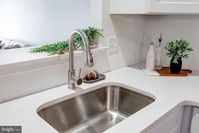 room details featuring light countertops, white cabinets, and a sink