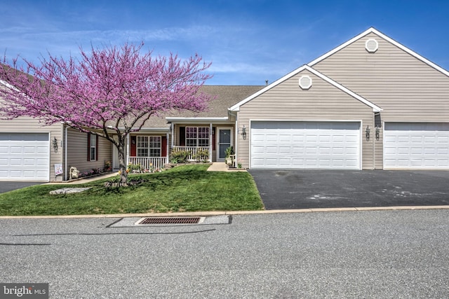 view of front facade featuring covered porch, an attached garage, a front yard, and aphalt driveway