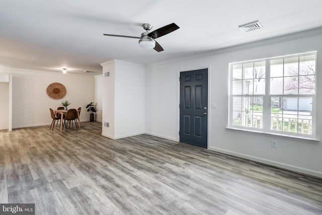 interior space with ornamental molding, wood finished floors, visible vents, and ceiling fan