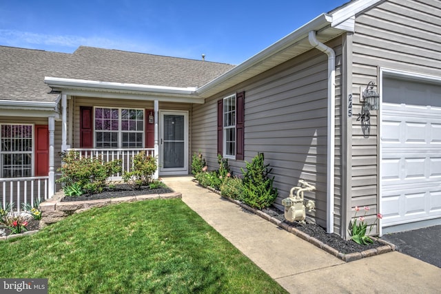 entrance to property with a yard, an attached garage, a porch, and roof with shingles