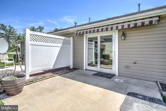 view of exterior entry with fence and a patio area