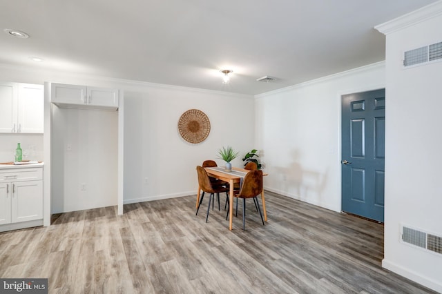 dining room with light wood-type flooring, visible vents, and crown molding