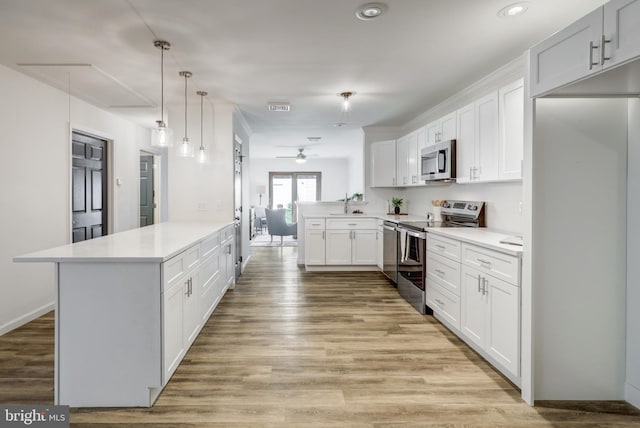 kitchen with a peninsula, light countertops, ceiling fan, and stainless steel appliances