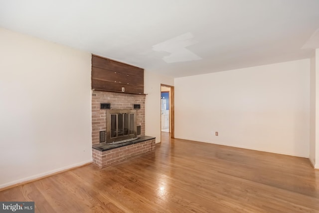 unfurnished living room featuring light wood-style flooring and a brick fireplace