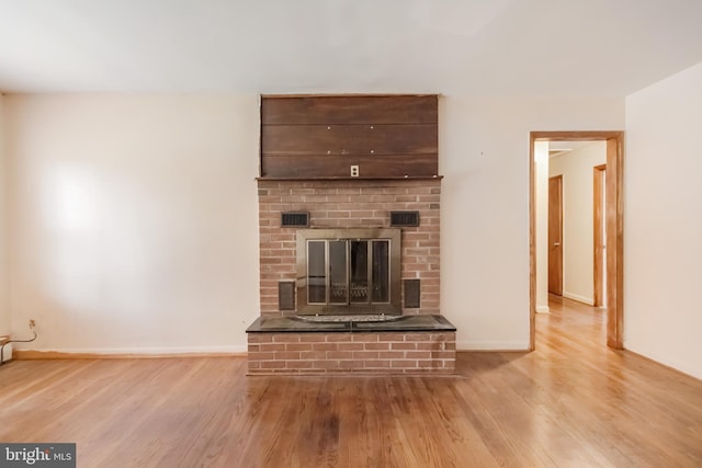 unfurnished living room with a fireplace, wood finished floors, visible vents, and baseboards