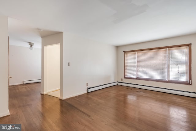 unfurnished room with a baseboard heating unit, wood finished floors, baseboards, and baseboard heating