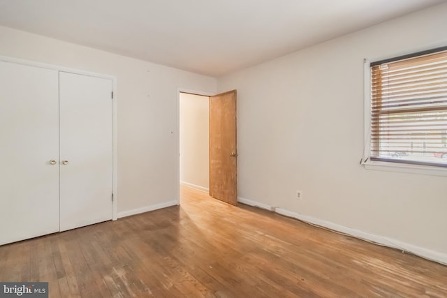 unfurnished bedroom with baseboards, wood finished floors, and a closet