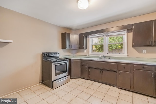 kitchen featuring stainless steel range with electric cooktop, dark brown cabinetry, a sink, and light countertops