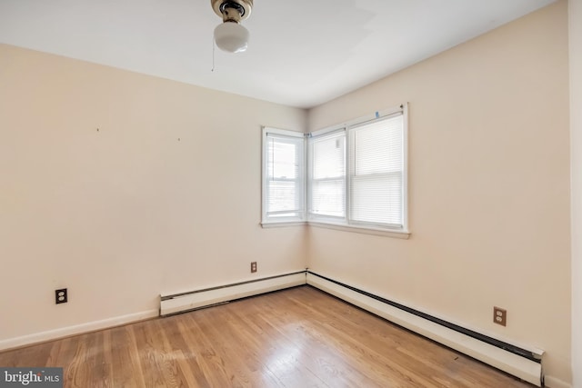 empty room with baseboard heating, baseboards, and light wood-style floors