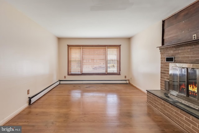 unfurnished living room with a baseboard radiator, wood finished floors, a fireplace, baseboards, and visible vents