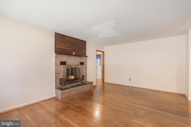 unfurnished living room featuring a brick fireplace and light wood-style flooring