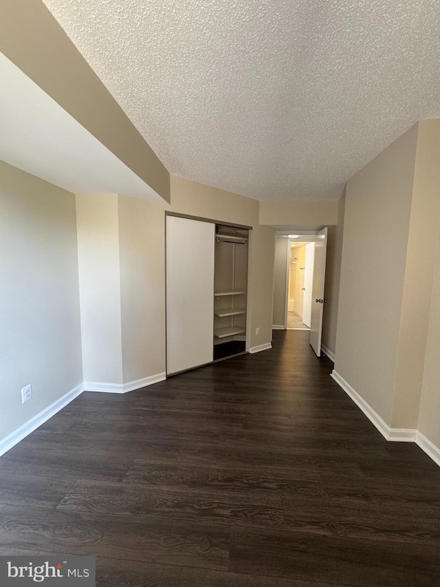 803 N Howard St Unit 435, Alexandria, VA 22304 - unfurnished bedroom with baseboards, dark wood-type flooring, a textured ceiling, and a closet