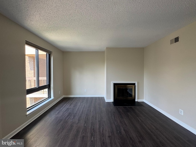 803 N Howard St Unit 435, Alexandria, VA 22304 - unfurnished living room featuring dark wood-type flooring, a textured ceiling, a fireplace with flush hearth, and baseboards