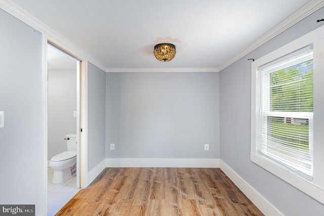 spare room featuring crown molding, baseboards, and light wood-style floors