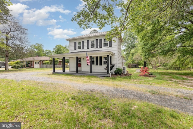 view of front of house with a front lawn, fence, a standing seam roof, a porch, and driveway