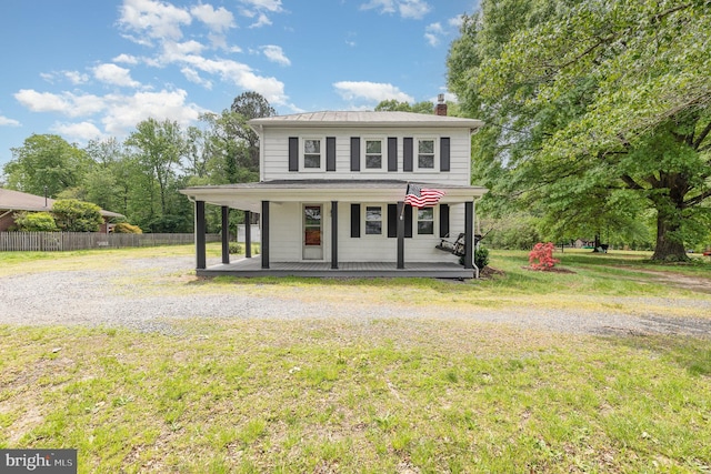 view of front of property featuring fence, a chimney, a porch, and a front lawn