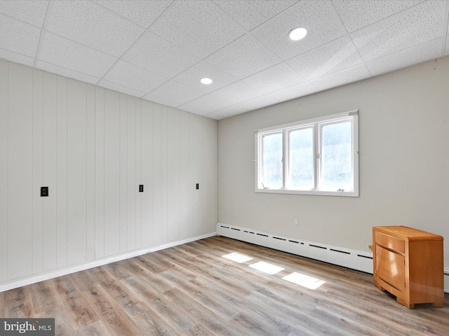 interior space featuring a baseboard heating unit, wood finished floors, baseboards, and recessed lighting