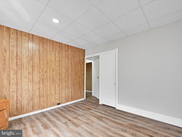 empty room with a paneled ceiling, wood finished floors, and baseboards
