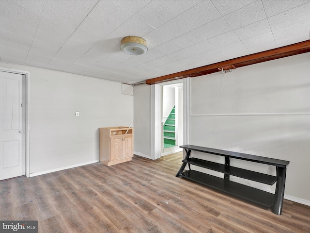 finished below grade area featuring baseboards, wood finished floors, and stairway